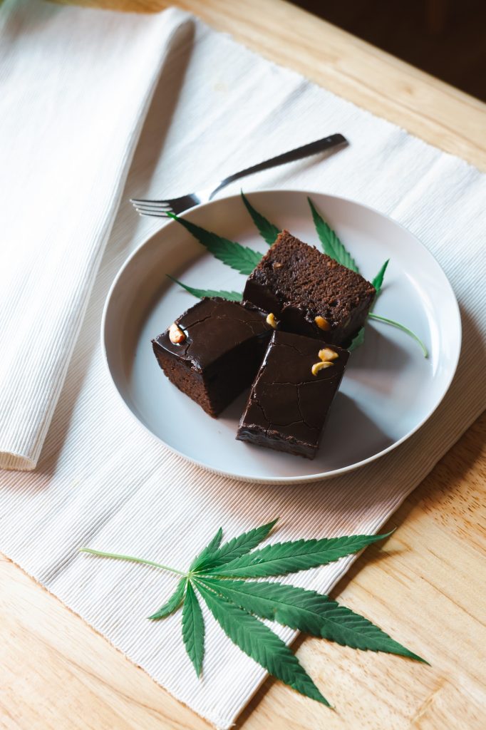 Homemade sweetmeat with marijuana or cannabis leaf on white plate. Alternative medicine concept.
